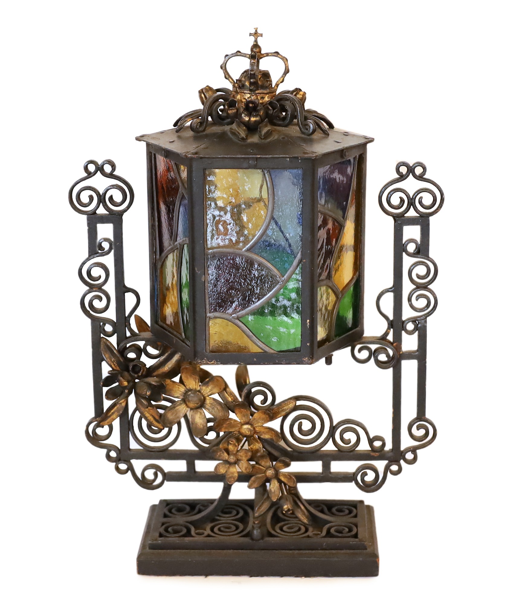 An early 20th century English wrought iron and stained-glass hexagonal lantern style table lamp with crown finial and parcel built black painted finish, height 50cm. width 32cm
